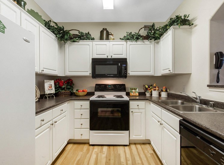Fully Equipped Model Kitchen with White Cabinets Grey Counters and  Decorations